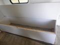 An empty cubby space with a white wooden top in a trailer interior designed for storage or seating