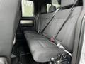 The back seat of a 2014 Ford F-150 featuring three seat cushions with seat belts and textured fabric upholstery