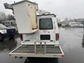 A white 2008 Ford Econoline van with a bucket lift attached to the rear and a flatbed platform underneath