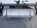 A metal plow attachment for a truck with a spring mechanism and a flat, wide blade designed for snow or debris removal