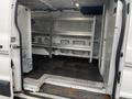 Interior of a 2018 Ford Transit van featuring metal shelving units along the walls and a rubber mat on the floor