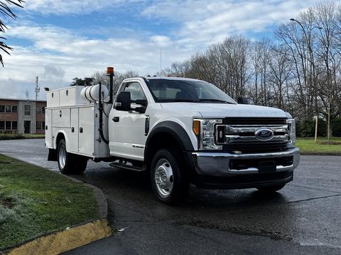 2017 Ford F-550 in white with a service body equipped with a large tank and tool compartments on the side