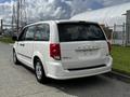 A white 2011 Dodge Grand Caravan parked with its rear view highlighted showing the tail lights and bumper