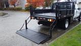 A black 2011 Ford F-550 flatbed truck with a lowered ramp designed for loading and unloading materials