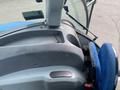 Interior view of a 2016 New Holland T475 tractor showing the control panel and driver's seat in blue fabric