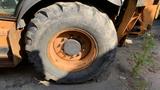 Close-up of a large tire on a 2015 Case 580 construction vehicle showing tread patterns and wheel details