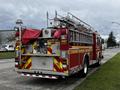 A red 2009 Spartan Gladiator fire truck with a ladder on top and reflective stripes on the sides parked along a roadside