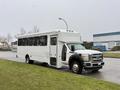 A white 2011 Ford F-550 bus with multiple windows parked on a street