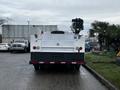 A white 2009 Ford F-550 truck with a flatbed and a mounted equipment compartment at the rear