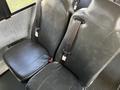 Two black leather seats with seat belts in a bus interior
