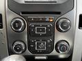 Interior console of a 2014 Ford F-150 featuring buttons for volume air conditioning and controls for navigation and settings