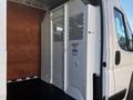 A white 2019 RAM Promaster cargo van interior featuring a partition with metal mesh and wooden panels on the sides