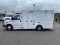 A white 2014 Chevrolet Express van with multiple side doors and lights on the roof parked on a flat surface