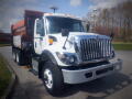 A 2016 International WorkStar 7500 truck with a white cab and an orange dump body, featuring a front grille with vertical bars and multiple lights on the roof.