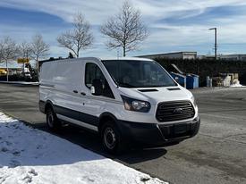 A white 2018 Ford Transit van with a black grille parked on a snowy surface