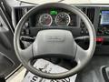 A 2022 Isuzu NPR steering wheel with controls for headlights and wipers and a dashboard featuring speedometer and fuel gauge displays