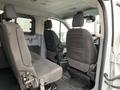 Interior view of a 2017 Ford Transit with two rows of gray fabric seats and a spacious cabin area