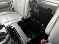 A black metal console compartment in the front seating area of a 2011 Ford Econoline with gray fabric seats