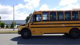 A yellow 2014 Freightliner Thomas diesel school bus parked with large windows and a blue light on the roof