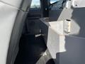 A gray storage compartment inside the back of a 2013 Ford F-250 SD with visible wear and rust