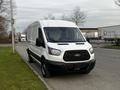 A 2017 Ford Transit van in white with a black grille and side mirrors parked on a street