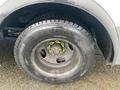 A close-up of a tire from a 2012 Chevrolet Express showing the wheel rim and bright green lug nut covers on a black Michelin tire