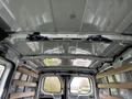 Interior view of a 2023 Ford Transit cargo van showing a metal roof structure with wooden shelves installed on the sides