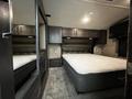 Interior of a 2021 Grand Design Recreational 311BHS featuring a queen-sized mattress with a headboard and built-in storage cabinets above