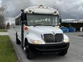 A white 2013 International 4200 school bus with a prominent front grille and multiple orange lights on the roof