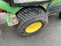 A 2014 John Deere 1585 Terrain Cut featuring a large black tire with a yellow rim and a green mud guard attached to the body of the machine