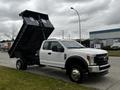 A white 2019 Ford F-550 with a raised dump bed showcasing its large wheels and chrome rims