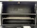 A 2016 Ford F-550 Super Duty truck with an open storage compartment featuring metal shelves and a dark interior