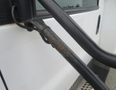 A close-up of a 2020 Chevrolet Express door handle showing a metal rod with a slight rust and the vehicle's exterior in white