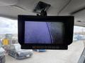 A rearview monitor displaying a hazy image of the ground, mounted on the roof of a vehicle interior