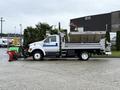 A white 2013 Ford F-650 truck equipped with a plow attachment and a large metal bed for carrying materials