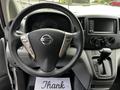 A steering wheel and dashboard of a 2020 Nissan NV200 with controls and a gear shifter visible in the foreground