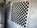 A textured metal panel with numerous circular holes is inside a vehicle, likely part of the interior of a 2016 GMC Savana cargo area