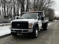 A 2008 Ford F-450 SD truck with a flatbed and a utility rack, featuring a black front grille and amber warning lights on the roof