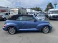 A blue 2007 Chrysler PT Cruiser convertible with a black soft top is parked among various vehicles, showcasing its distinctive shape and chrome wheels