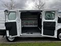 A 2023 Ford Transit van with its side doors wide open, revealing a spacious interior with wooden shelves and a black rubber floor mat