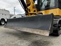 A yellow Caterpillar 306 excavator with a large black blade attachment displayed in the foreground