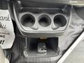 The interior console of a 2020 Chevrolet Express featuring three cup holders and a small storage compartment below
