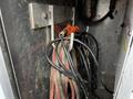 A bundle of black and red electrical cables with a bright orange connector, housed in a metallic compartment of a vehicle