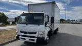 A 2018 Mitsubishi Fuso FE truck with a white box cargo container and an extended cab parked on a paved area