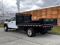 A 2019 Ford F-550 truck with a flatbed and black siding parked at an industrial area