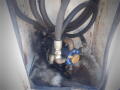 A close-up view of a black and blue pump assembly with multiple hoses connected to it inside a compartment of a 2005 Ford F-750