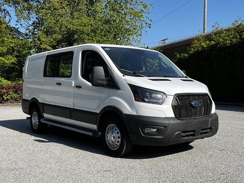 A 2023 Ford Transit in white with a black grille and front bumper facing slightly to the right with no rear windows and a sliding side door