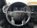 Steering wheel of a 2022 Toyota Tacoma featuring controls for media and cruise settings along with the Toyota logo in the center