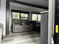 The interior of a 2022 Aspen Trail featuring two grey recliner chairs and a central kitchen area with cabinets and a counter