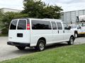 A white 2021 Chevrolet Express van with tinted windows and chrome wheels parked with its back facing the viewer